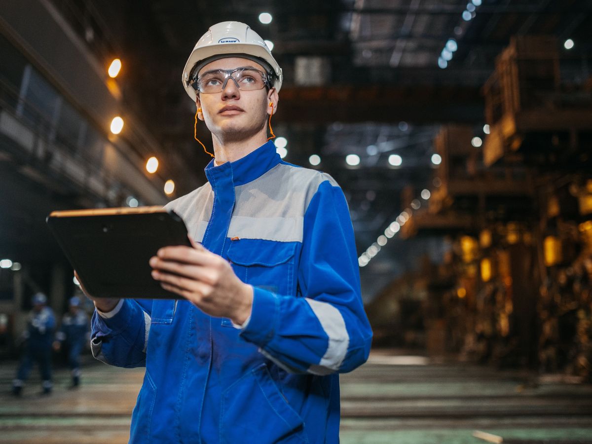 Maintenance engineer completing a work order on a tablet on a plant floor